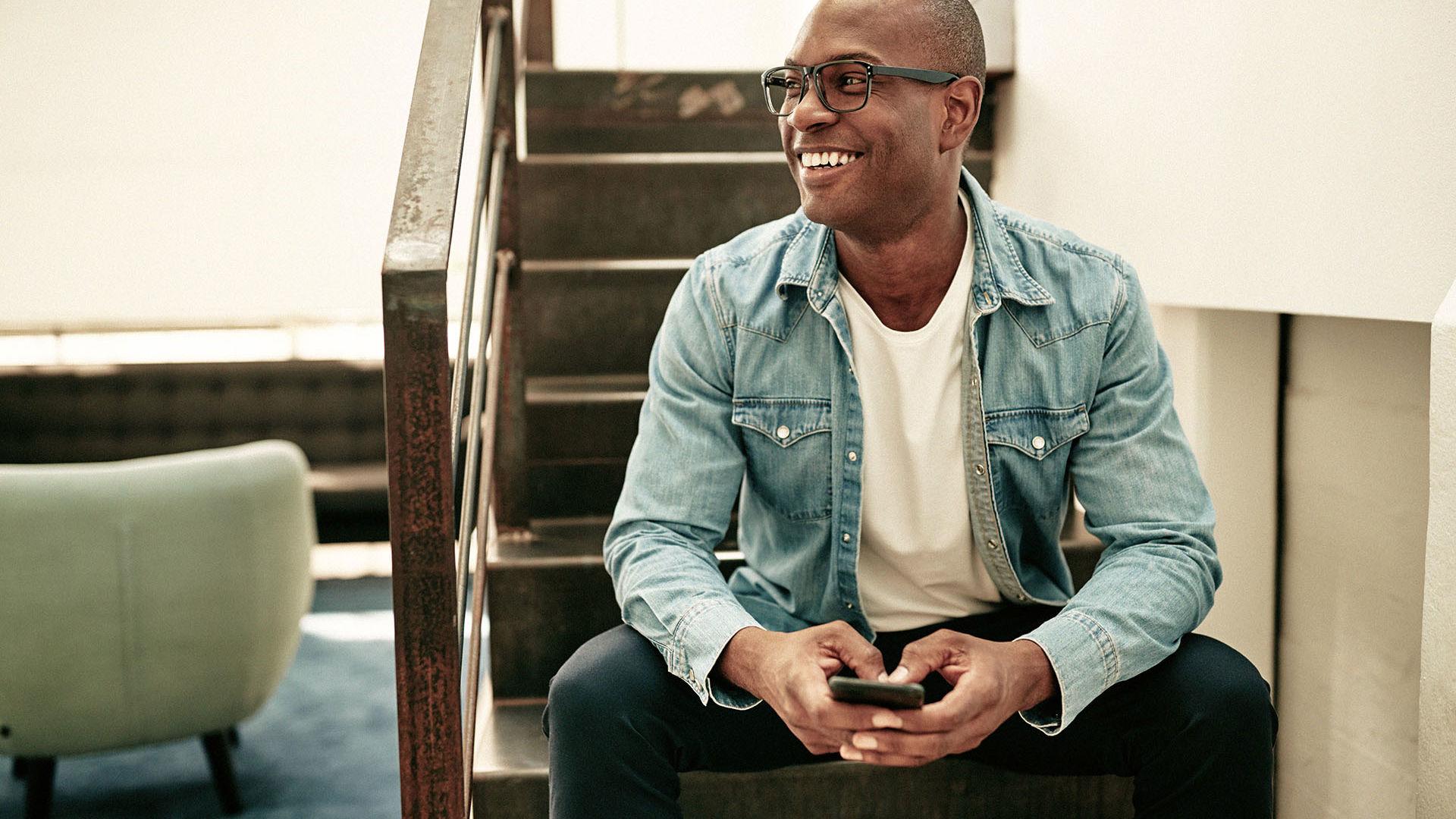 Man sitting on stairs wearing glasses on phone