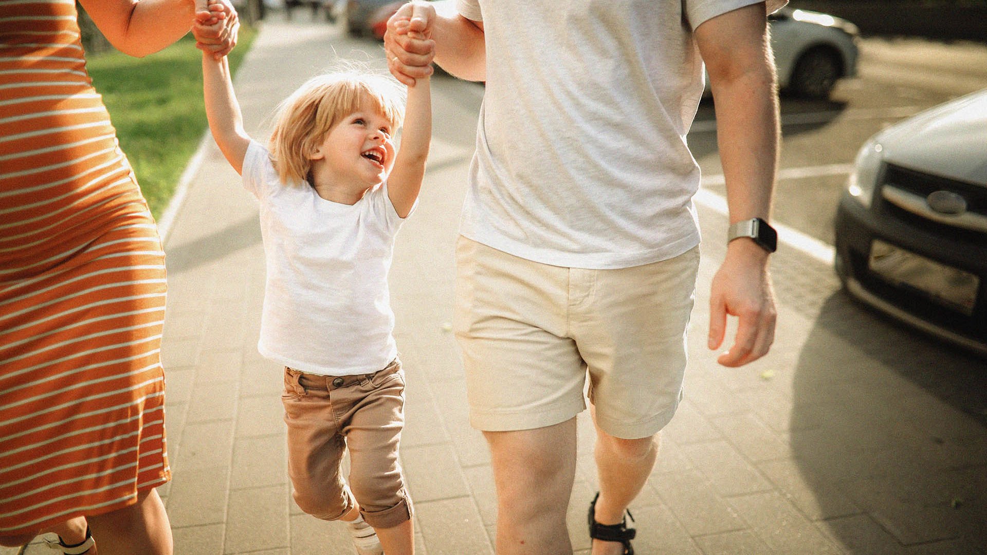 Little boy smiling while his parents swing him
