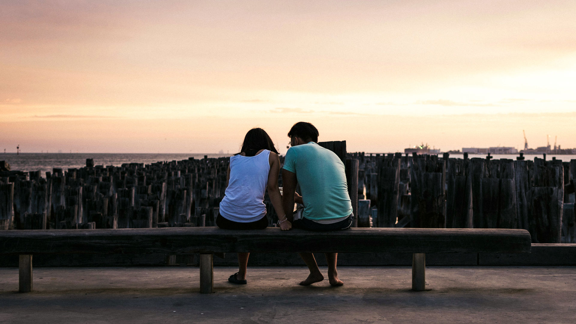 young couple sitting on pier looking at water thinking about life