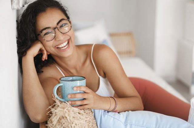 Smiling young woman lying on couch wearing glasses