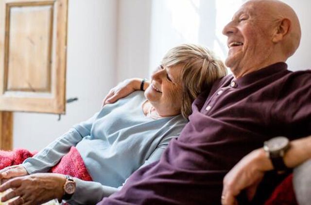 Older couple laughing together on the couch