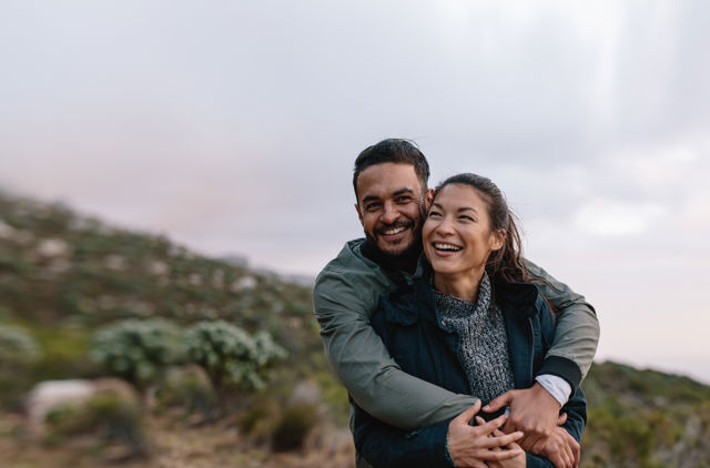 Young couple cuddling outside looking happy