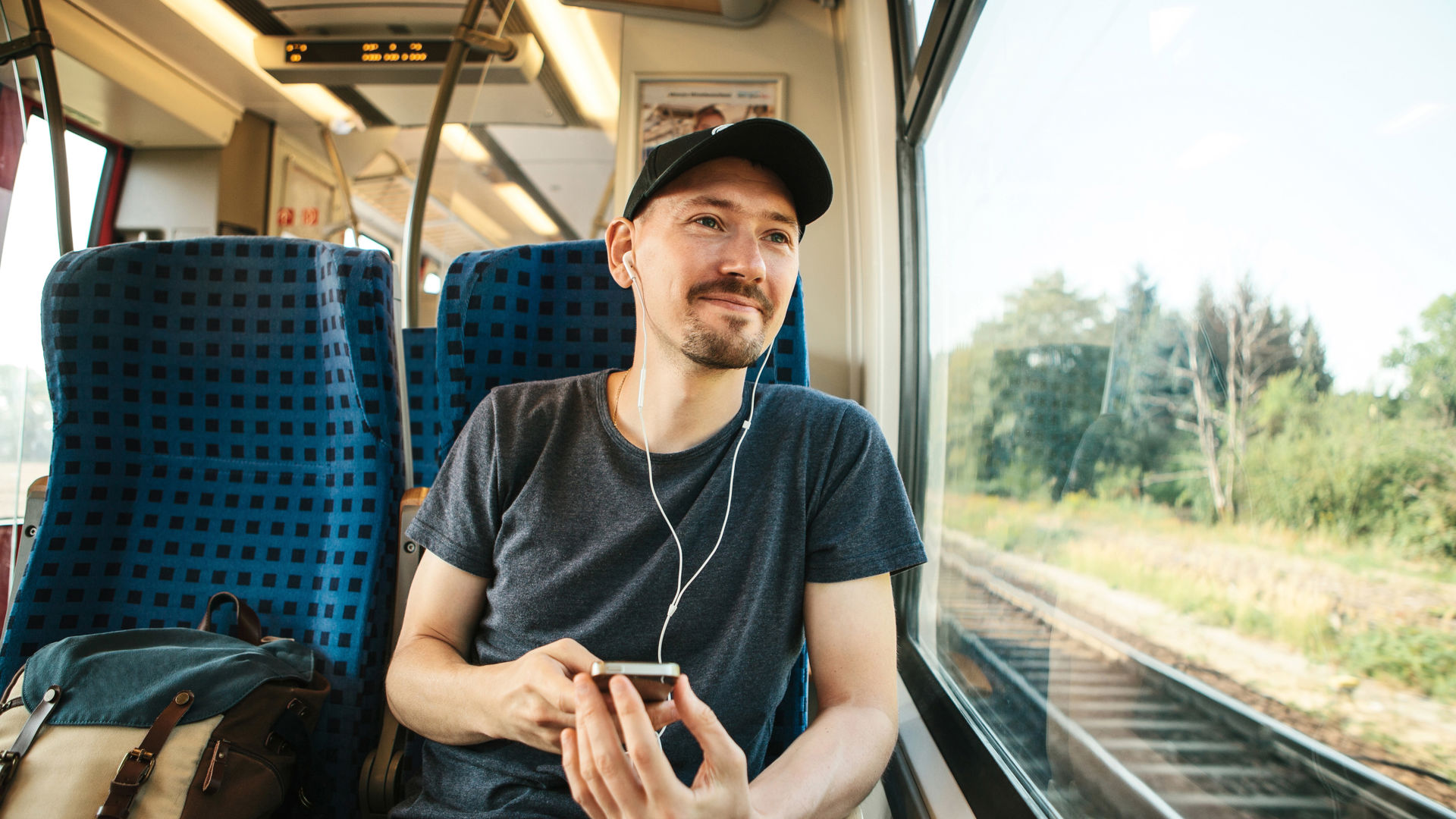 man sitting on the train listening to a podcast