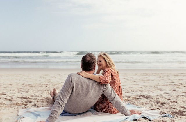 Over 60s couple relaxing on the beach with peace of mind for their private health insurance