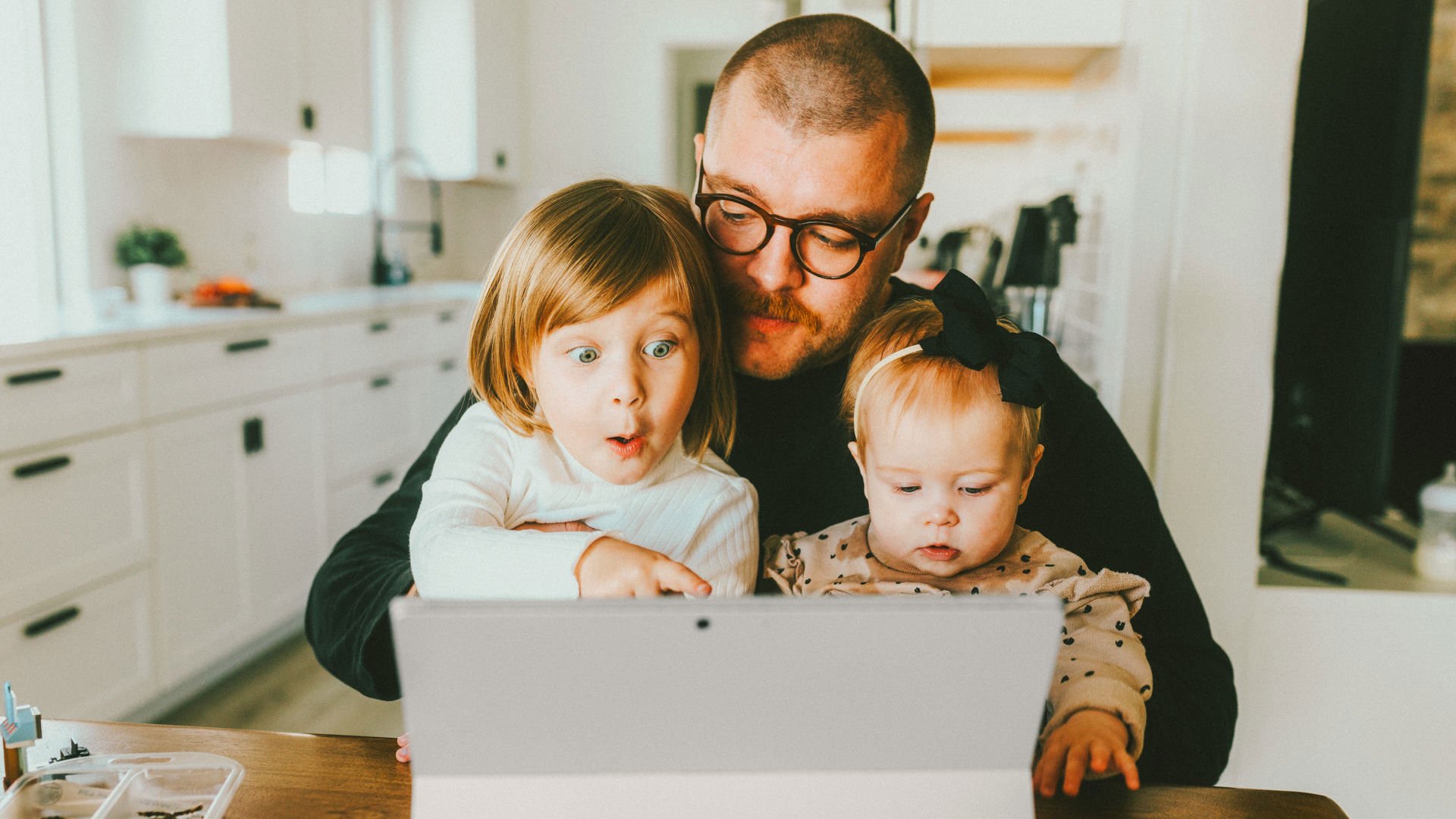 Dad on Laptop looking at health insurance with children on lap