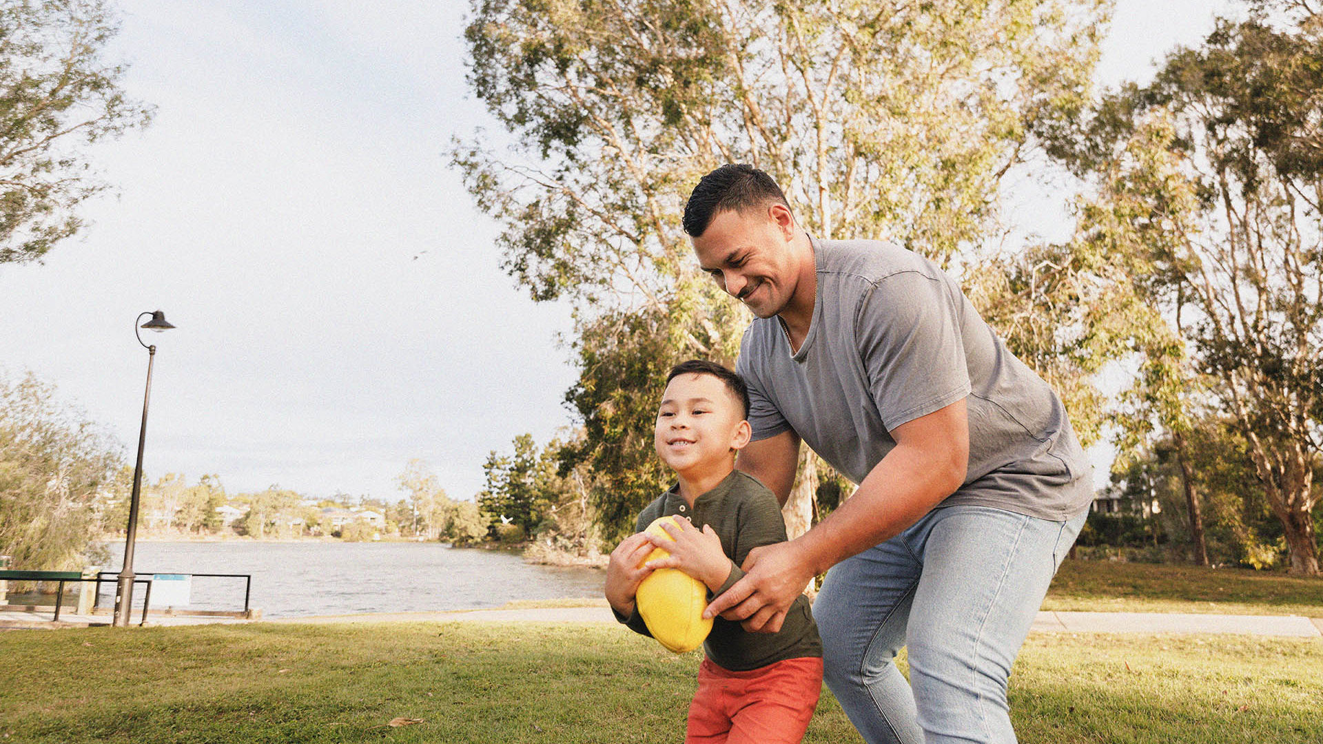 Young GMHBA father and son playing footy in the park