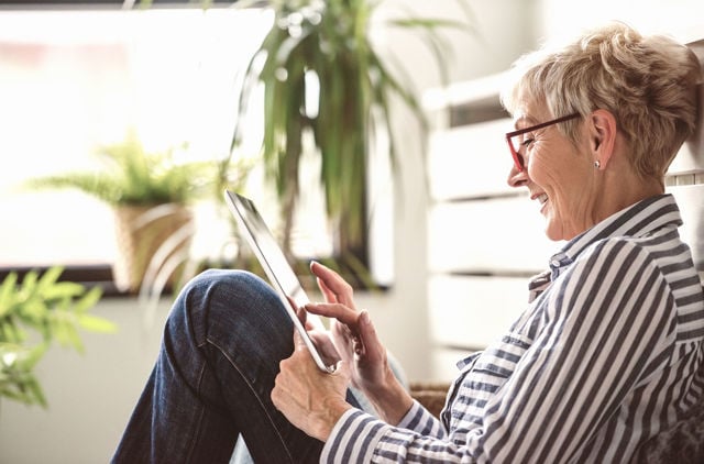 Senior woman using digital table to look up GMHBA hospital cover